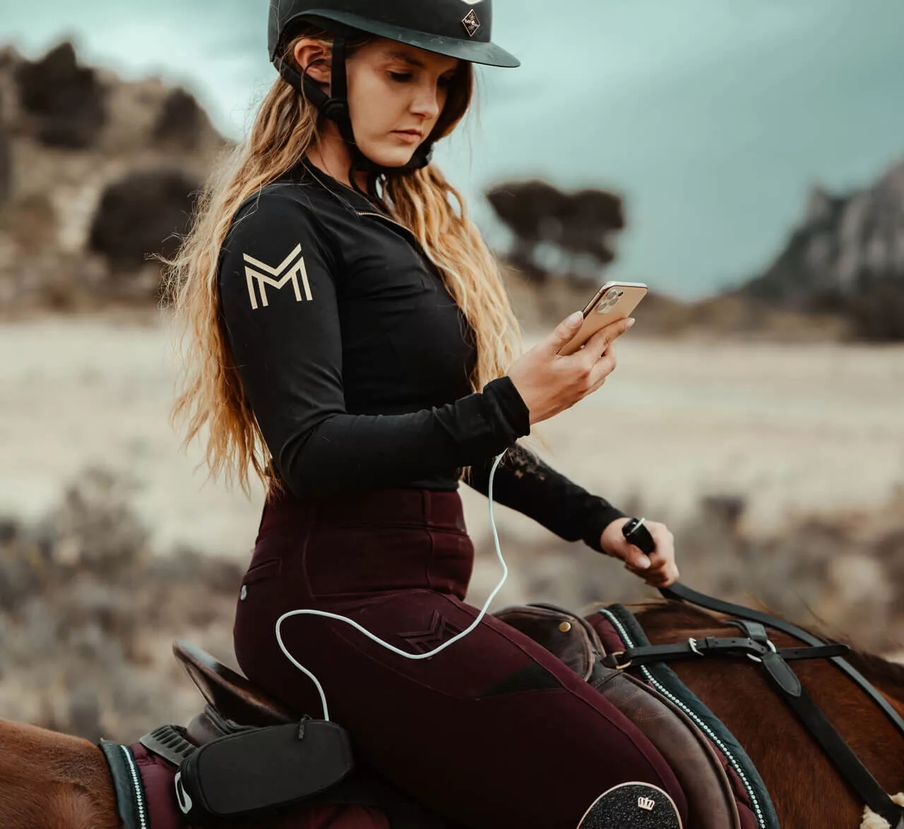 Frau auf einem Pferd mit Handy in der Hand
