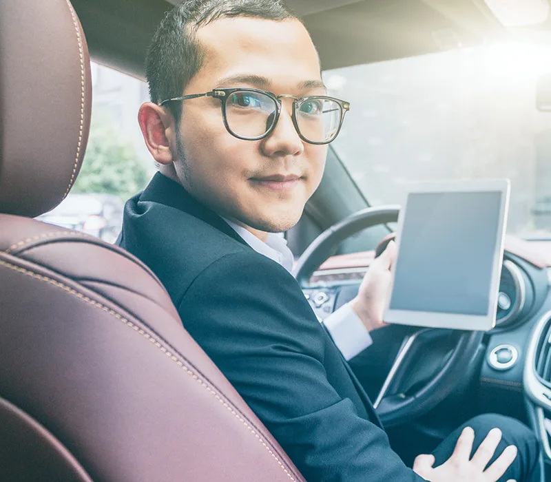 Ein Mann in einem Auto fuehrt sein Fahrtenbuch.