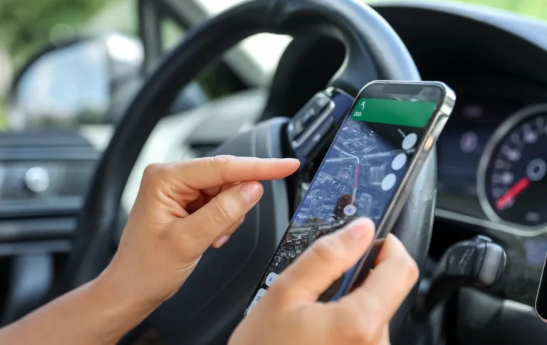 Female driver hand holding a phone with interface navigator on a screen