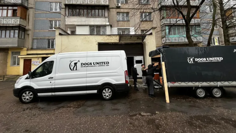 Transporter und Anhänger von Dogs United werden vor einem Wohnblock in der Ukraine beladen