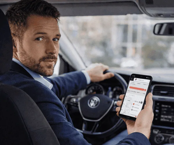 Ein Mann in einem Auto fuehrt sein Fahrtenbuch.