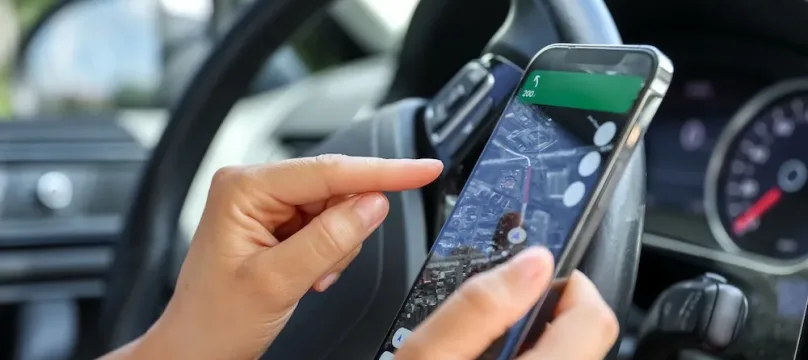 A woman driving a car use your smartphone to view a map showing your travel route and use the application to get to the destination.